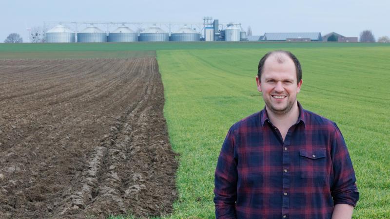 Dieter Duchateau toont de velden waar hij gerst teelt, met op de achtergrond de boerderij van hem en zijn familie.