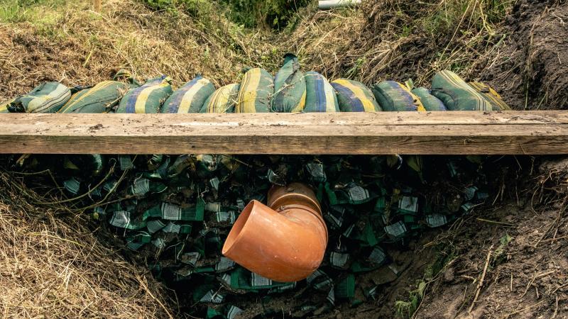 Het tijdelijke stuwdammetje met zandzakken en pvc-buizen in de Krekelstraat in Zwijnaarde.