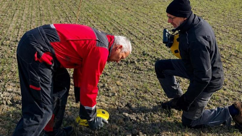 Landbouwer Jos De Potter (links) en een vrijwilliger van vzw De Kerkuil plaatsen een beschermend schaaltje over een nest kievitseieren.