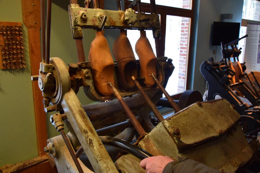 De klompenmaker volgt de vorm van het model in het midden, zodat messen machinaal een paar klompen uitsnijden.