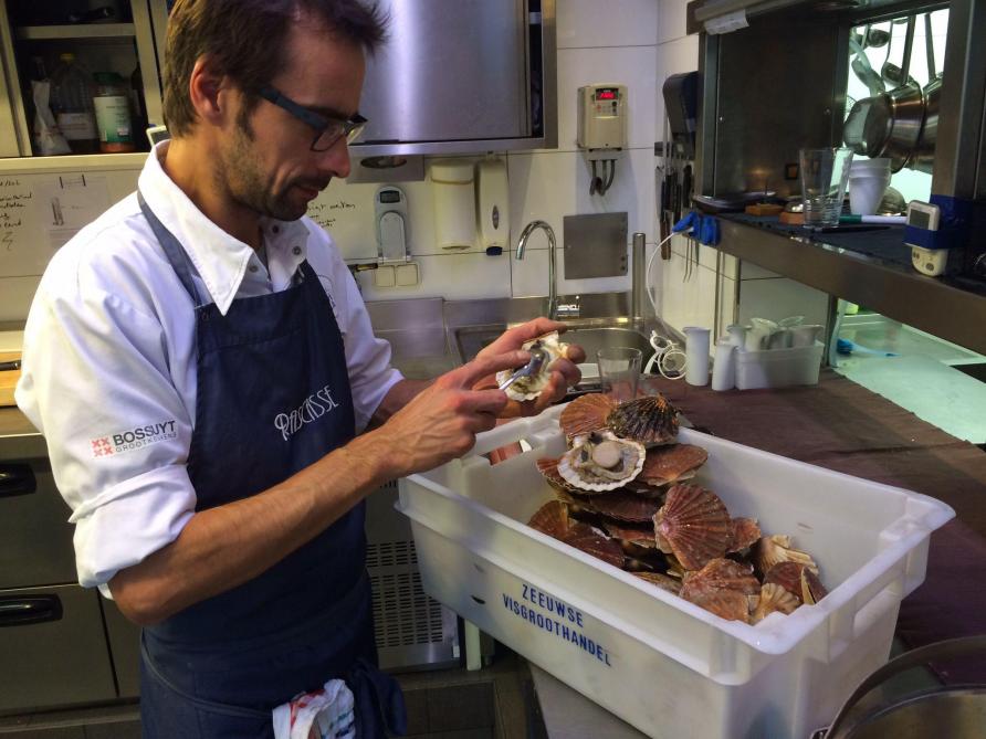 Chef Erwin Denys van Rascasse terwijl hij Sint-Jakobsschelpen kuist.