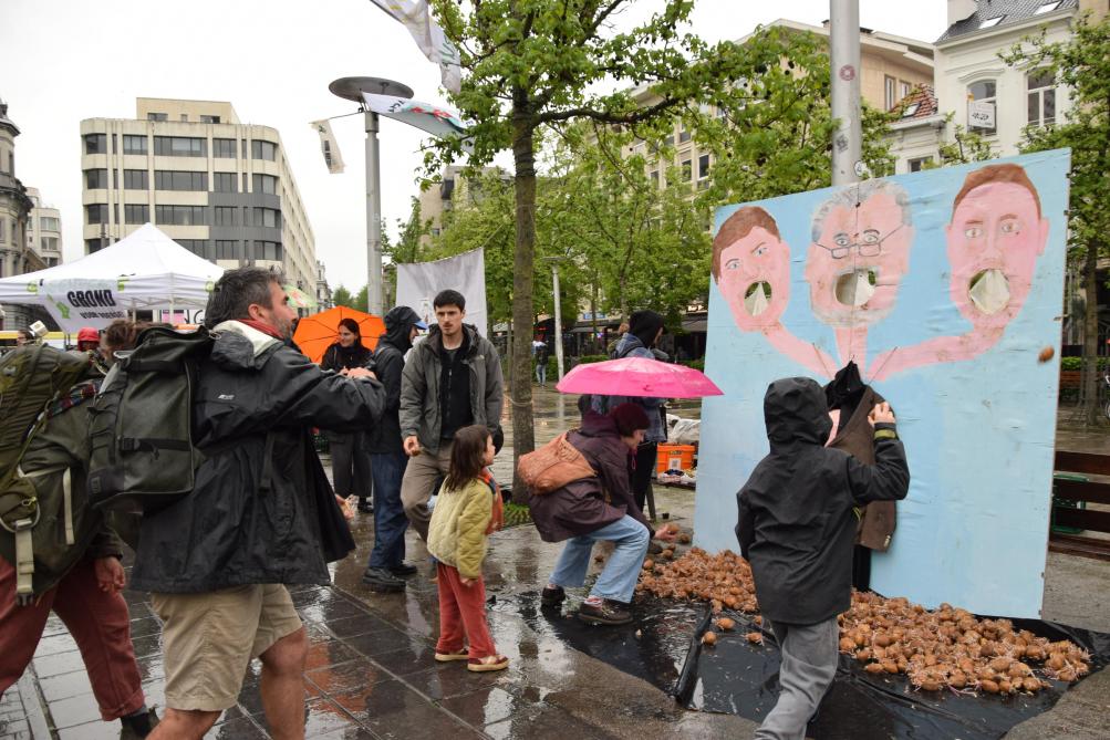 Actievoerders, jong en oud, gooien ‘verzetspatatjes’ door de monden van het driekoppige monster: de agro-industrie, het kapitalisme en de politiek.