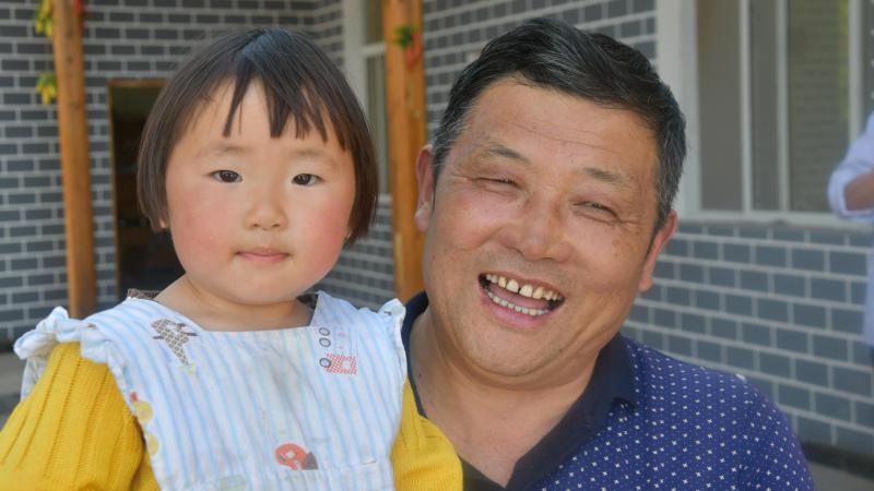 De heer Lu en zijn dochtertje van twee jaar in het dorp Tujiazhai: “De Taobao Shop draagt zeer sterk bij tot de ontwikkeling van de fruitcoöperatie die werk biedt aan tal van families in het dorp.”