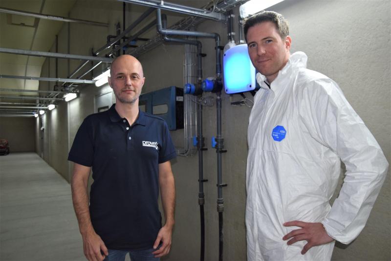 Pascal Defoort (links) en Dries Berckmans in de centrale gang van varkensbedrijf Wallehoek. De routers stralen er blauw ligt uit.