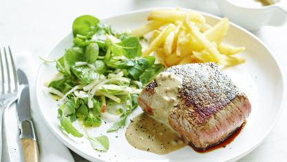 Geflambeerde pepersteak met sla en frietjes.