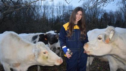 Chloë op haar gemak tussen de koeien met het fruitsap dat ze voor het goede doel verkoopt. De affectie is wederzijds.