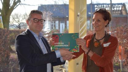 Minister Koen Van den Heuvel krijgt het boek overhandigd door Nik Van Gool voorzitter van de KVLV.