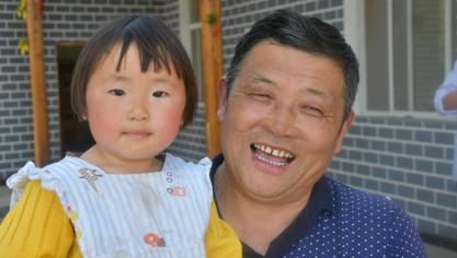 De heer Lu en zijn dochtertje van twee jaar in het dorp Tujiazhai: “De Taobao Shop draagt zeer sterk bij tot de ontwikkeling van de fruitcoöperatie die werk biedt aan tal van families in het dorp.”