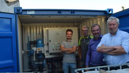 V.l.n.r. Daan Rooms, Eric Scheers, Kris Moerman en Geert Verhiest gaven toelichting bij het proefproject ‘fertigatie’. Op de achtergrond de container met installatie, op de voorgrond de containers met vloeibare meststoffen.