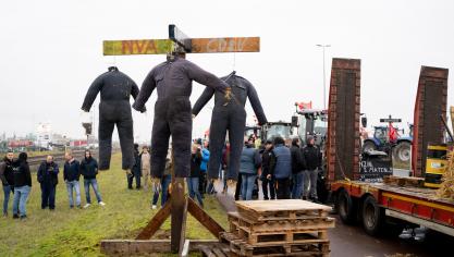 De 3 poppen in overals staan voor boeren die de das omgedaan worden door de partijen N-VA, Open VLD en cd&amp;v.