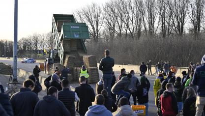 Een boer laadt op zondag 28 januari strobalen uit om een barricade te maken op de kruising tussen de E40 en E411 in Daussoulx.