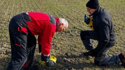 Landbouwer Jos De Potter (links) en een vrijwilliger van vzw De Kerkuil plaatsen een beschermend schaaltje over een nest kievitseieren.