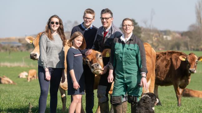 Omringd door hun drie kinderen, poseren Bernard en Delphine voor een deel van hun veertigtal Jerseykoeien. Een ras dat hen volledige voldoening schenkt.