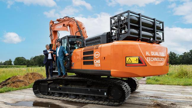 Jos Luyckx - CEO Luyckx (l) en Roy Campe - CTO CBM.TECH (r) bij de Hitachi graafmachine die zij voorzagen van de dual fuel technologie waarbij de dieselmotor een deel waterstof bij mengt.