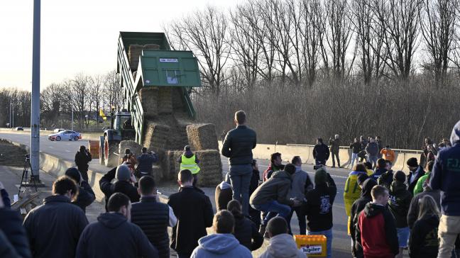 Een boer laadt op zondag 28 januari strobalen uit om een barricade te maken op de kruising tussen de E40 en E411 in Daussoulx.