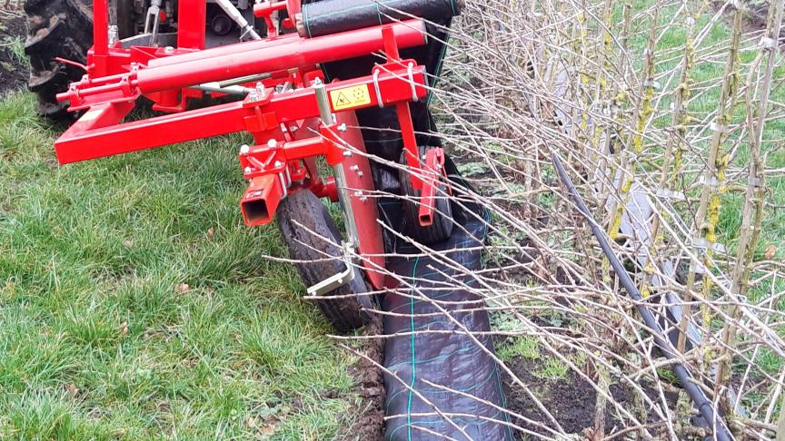 De machine rolt de worteldoek uit.