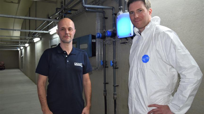 Pascal Defoort (links) en Dries Berckmans in de centrale gang van varkensbedrijf Wallehoek. De routers stralen er blauw ligt uit.