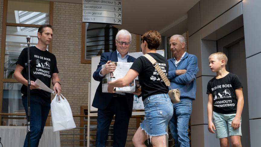 Melkveehoudster Nicky Van Otten geeft de burgemeester de doos met bezwaarschriften.