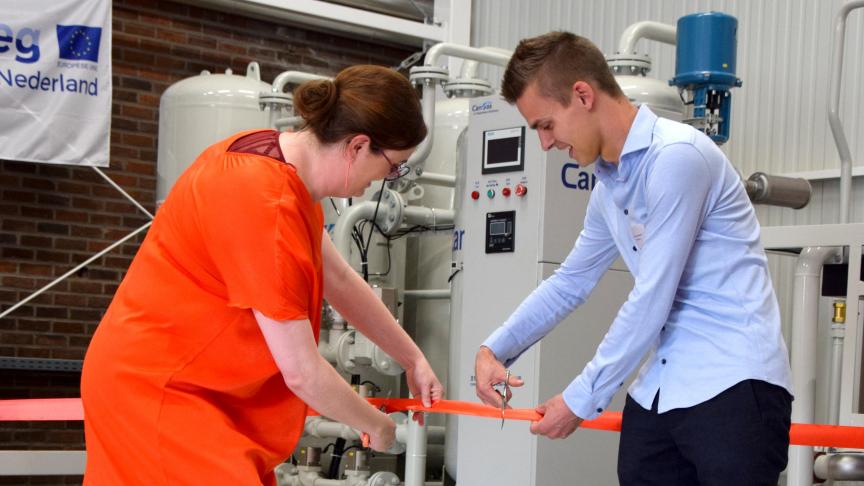 Sofie Mols, directeur innovatie en internationalisering van Thomas More, en tuinder Mitch Vermeiren, voorzitter van de Kempische Glasgroentenkring, knippen het lint bij de opening van de CO 2 -zuiveringsinstallatie.